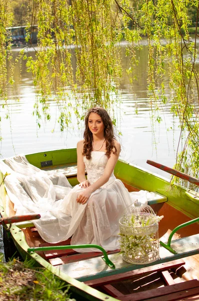 Fantasy portrait of elegant bride in white wedding dress boating on river