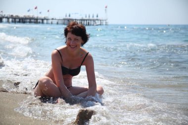 Güzel bir kadın güneşin denizin tadını çıkarma. Sahilde oturan bir genç bayan. Kumsalda güneşlenirken güzel yetişkin kadın. 