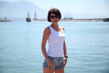 Güzel kız deniz arka plan üzerinde kamera için poz. Model yaz gün sahilde poz.