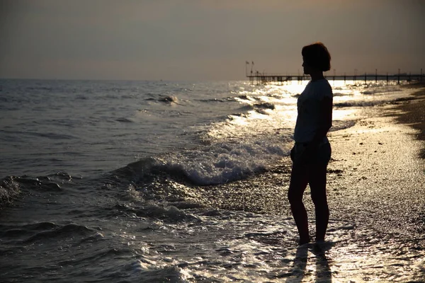 美しい女性が海で日光浴します ビーチに座っている若い女性 ビーチでの日光浴のアダルト美人 — ストック写真