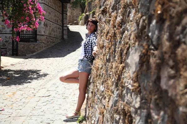 Bir kız bir eski şehir sokak kaldırım taşları ile döşeli bir kamera için poz. Sokak. Sanat güzel eski şehir Alanya