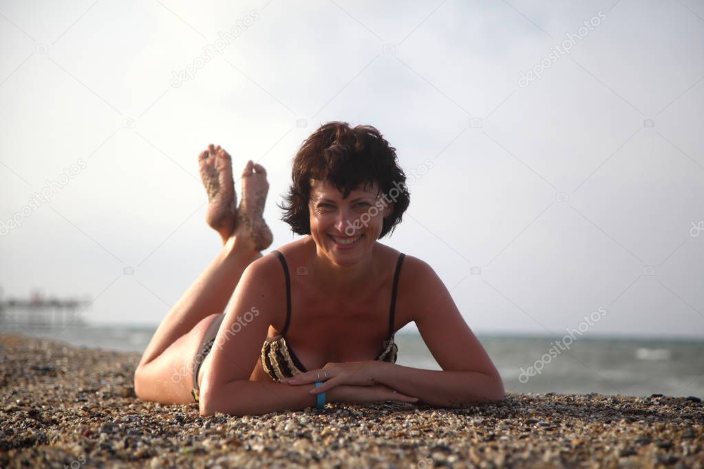 A beautiful woman is basking in the sun in the sea. Young woman sitting on the beach. Beautiful adult woman sunbathing on the beach. 