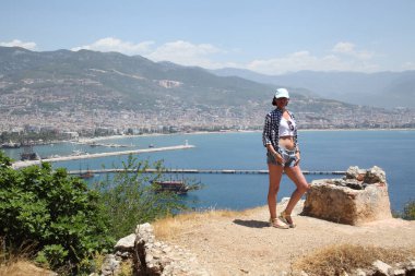 Alanya Alanya Yarımadası limandan görünümü. Türkiye sahillerinde. Güzel kız deniz arka plan üzerinde kamera için poz. Model yaz gün sahilde poz.