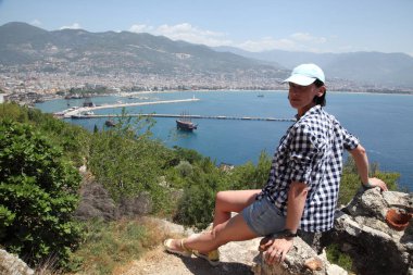 Alanya Alanya Yarımadası limandan görünümü. Türkiye sahillerinde. Güzel kız deniz arka plan üzerinde kamera için poz. Model yaz gün sahilde poz.