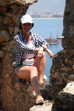 Alanya Alanya Yarımadası limandan görünümü. Türkiye sahillerinde. Güzel kız deniz arka plan üzerinde kamera için poz. Model yaz gün sahilde poz.