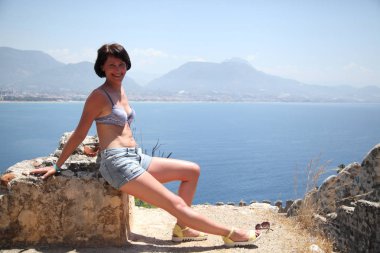 Alanya Alanya Yarımadası limandan görünümü. Türkiye sahillerinde. Güzel kız deniz arka plan üzerinde kamera için poz. Model yaz gün sahilde poz.