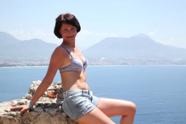 Alanya Alanya Yarımadası limandan görünümü. Türkiye sahillerinde. Güzel kız deniz arka plan üzerinde kamera için poz. Model yaz gün sahilde poz.