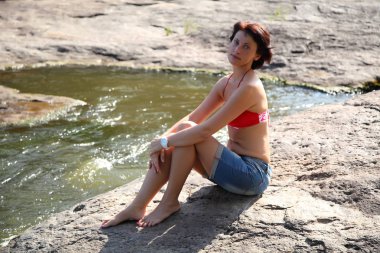 Nehrin yanında sahilde kadınla. Nehrin üzerinde bir tepe üzerinde yaz güneş ışınlarının güzel genç kadın banyoları. 