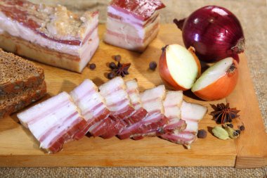 Bir ahşap tahta dilimlenmiş jambon, füme. Pastırma füme, kırmızı soğan, tuz ve biber bir kil çanak üzerinde. Füme domuz yağı.