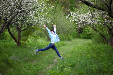 Bahar bahçesinde kamera için poz güzel olgun kadın. Kız elma ağaçlarının çiçekli sahiptir.