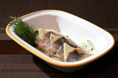 Beyaz tabakta kırmızı soğan, dereotu ve baharatlar ile marine ringa filetosu. Soğan limon ve dereotu ile Ringa filetosu.