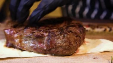 Eldivenli bir garson sulu bir biftek keser. Restoran şefi orta pişmiş biftek dilimliyor..
