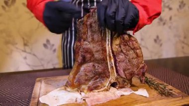 Eldivenli bir garson sulu bir biftek keser. Restoran şefi orta pişmiş biftek dilimliyor..