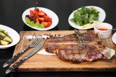 Orta pişmiş biftek, ahşap bir tahtanın üzerinde sos ve baharatlarla dilimlenmiş. Lezzetli biftek. Sebze yastığında az pişmiş biftek. Tahta tabakta biftek.. 