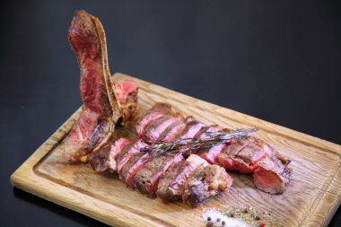 Orta pişmiş biftek, ahşap bir tahtanın üzerinde sos ve baharatlarla dilimlenmiş. Lezzetli biftek. Sebze yastığında az pişmiş biftek. Tahta tabakta biftek.. 