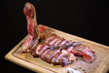 Orta pişmiş biftek, ahşap bir tahtanın üzerinde sos ve baharatlarla dilimlenmiş. Lezzetli biftek. Sebze yastığında az pişmiş biftek. Tahta tabakta biftek.. 