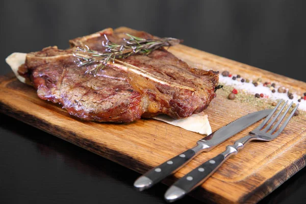 Medium-roasted steak cut into pieces on a wooden board with sauce and seasonings. Delicious steak. Beef steak medium rare on vegetable cushion. Beef steak on wooden plate.