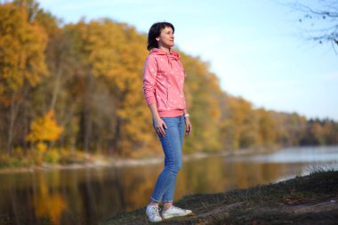 Sarı sonbahar orman içindeki kız. Güzel ve genç birbayan sonbahar orman yolu boyunca yürür.