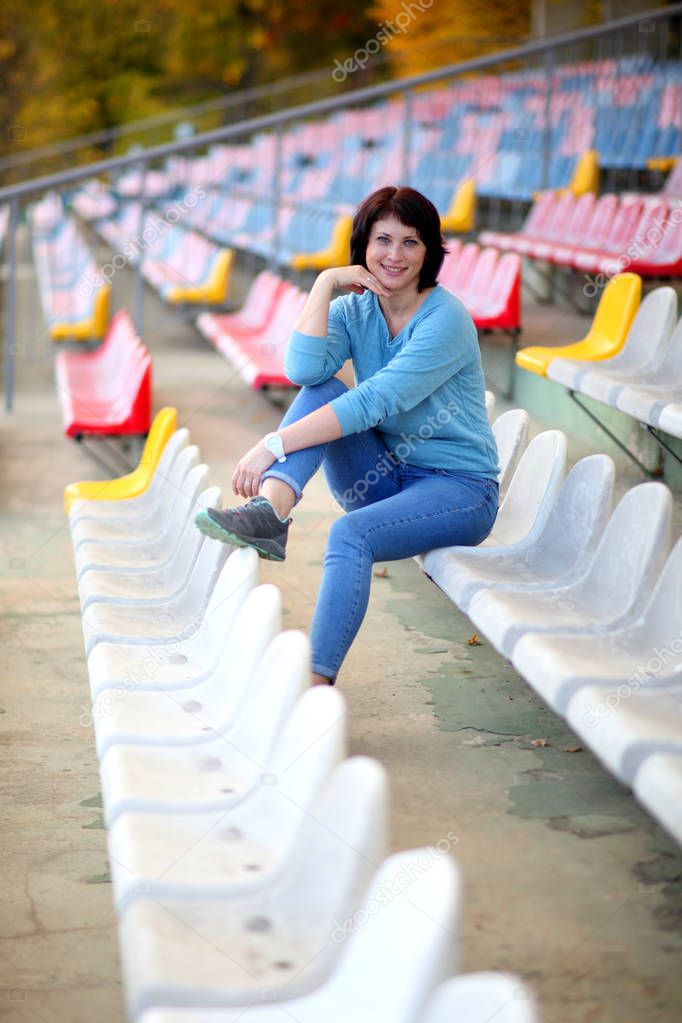 Beautiful woman in the stadium. Portrait of a fitness woman resting at outdoor stadium.