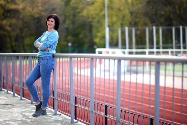 Vacker kvinna på arenan. Porträtt av en fitness kvinna vilar på utomhus stadion. — Stockfoto