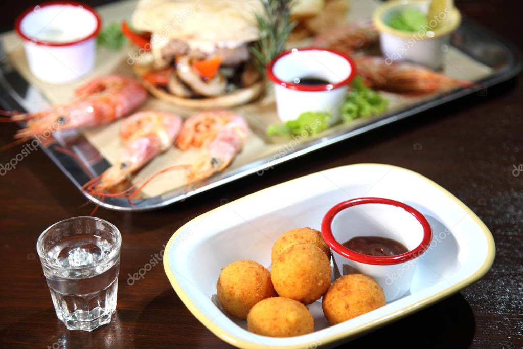 Fried balls of cheese. Cheese balls fried in breadcrumbs with sauce. Deep Fried Breaded Cheese. Burger and langoustines with sauce on a tray.