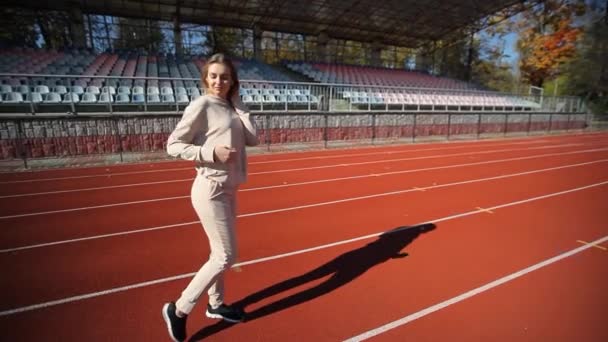 在一个红色跑步机上的体育场里 一位漂亮的年轻女子 一个女孩在体育场的跑步机上奔跑 年轻姑娘在体育馆里赛跑 — 图库视频影像