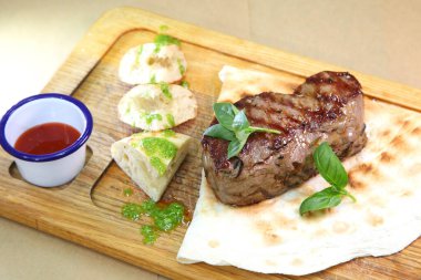 Orta pişmiş biftek, ahşap bir tahtanın üzerinde sos ve baharatlarla dilimlenmiş. Lezzetli biftek. Sebze yastığında az pişmiş biftek. Tahta tabakta biftek..