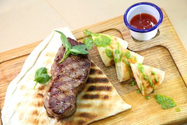 Orta pişmiş biftek, ahşap bir tahtanın üzerinde sos ve baharatlarla dilimlenmiş. Lezzetli biftek. Sebze yastığında az pişmiş biftek. Tahta tabakta biftek..