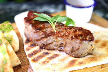 Orta pişmiş biftek, ahşap bir tahtanın üzerinde sos ve baharatlarla dilimlenmiş. Lezzetli biftek. Sebze yastığında az pişmiş biftek. Tahta tabakta biftek..