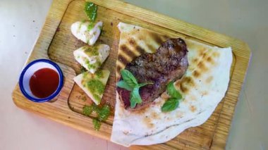 Orta pişmiş biftek, ahşap bir tahtanın üzerinde sos ve baharatlarla dilimlenmiş. Lezzetli biftek. Sebze yastığında az pişmiş biftek. Tahta tabakta biftek..