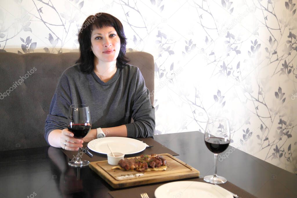 Girl eats steak with wine. Girl passionately eats steak. Steak and wine.