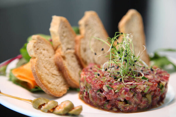 Raw tartar meat with spices, croutons and herbs. Beef tartar with capers. Beef tartar with slices of bread.  Raw meat tartare for gourmet meat.