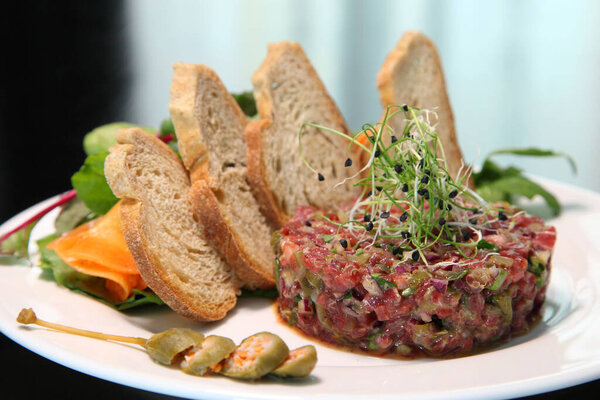Raw tartar meat with spices, croutons and herbs. Beef tartar with capers. Beef tartar with slices of bread.  Raw meat tartare for gourmet meat.