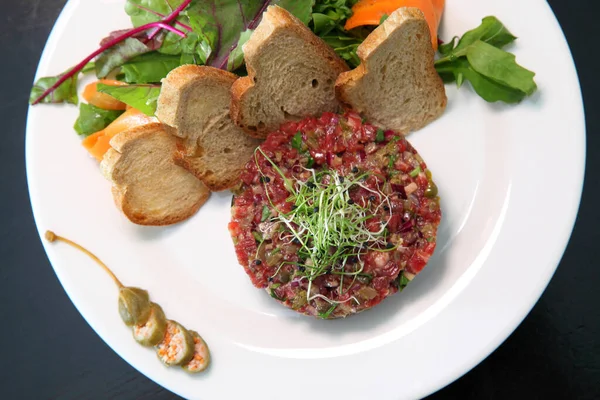 Raw meat tartare for gourmet meat. Raw tartar meat with spices, croutons and herbs. Beef tartar with capers. Beef tartar with slices of bread.
