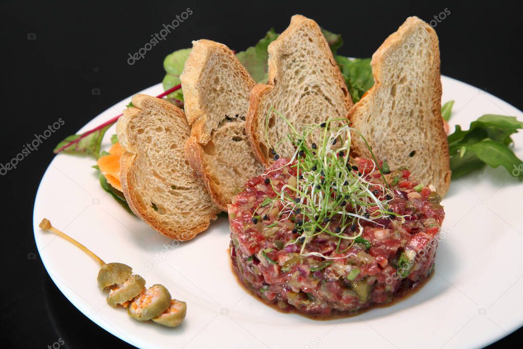 Raw tartar meat with spices, croutons and herbs. Beef tartar with capers. Beef tartar with slices of bread.  Raw meat tartare for gourmet meat.