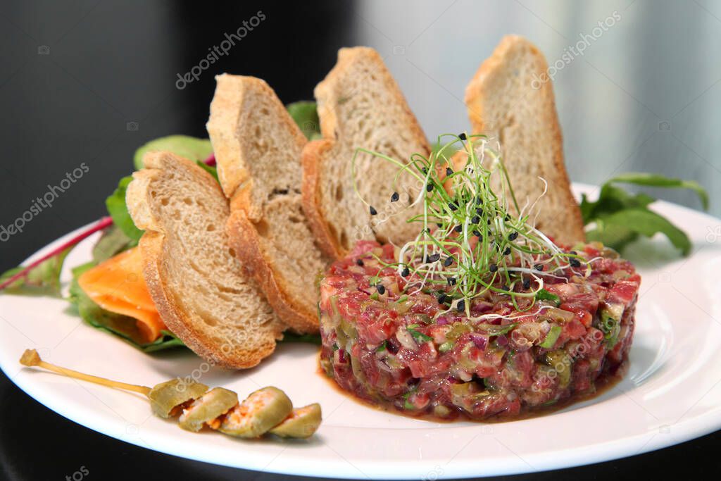 Raw tartar meat with spices, croutons and herbs. Beef tartar with capers. Beef tartar with slices of bread.  Raw meat tartare for gourmet meat.