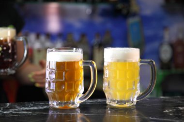 Farklı el yapımı biralı bardaklar. Barın üstünde kırmızı, bronz ve beyaz bira bardakları. Bar arka planında açık ve koyu bira bardakları. 