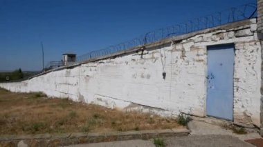 Eski hapishane. Hapis. Dikenli tel. Metal dikenli çitli beyaz duvar.