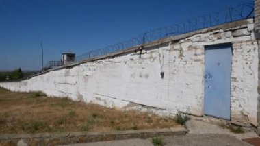 Eski hapishane. Hapis. Dikenli tel. Metal dikenli çitli beyaz duvar.