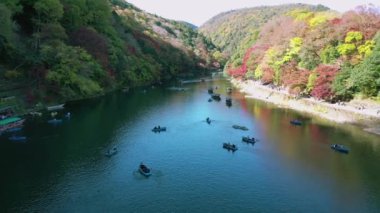 Sonbaharda Katsura nehrinin insansız hava aracı ve tekneleriyle 4k hava görüntüsü. Arashiyama, Kyoto, Japonya