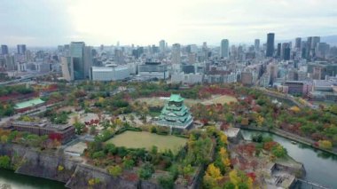 Sonbaharda Osaka, Japonya 'daki Osaka Kalesi ve inşaat şehrinin insansız hava aracı tarafından 4K görüntüsü.