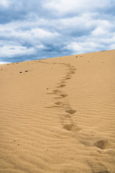 Footprints on the sand dunes. Mystical skies in the background.