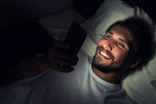 Pria muda berjenggot bahagia berbaring di tempat tidurnya dan tersenyum sementara wa — Stok Foto