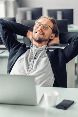 Genç adam iş yerinde müzik dinlerken dinlenmeye çalışıyor. C