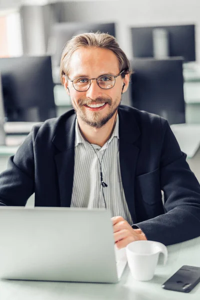 Handsome smiling young man with headphones sitting by the comput Royalty Free Stock Photos