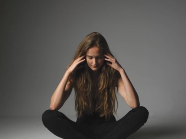 Düşüncelerimi odaklanmış durumdayım. Çekici uzun saçlı güzel kadın modeli sarışın katta oturan ve başını elleri ile tutar.