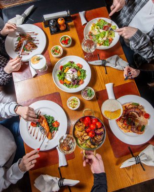 Tanımlanamayan arkadaş grubu restorandaki bir sette yemek yiyor. Üst görünüm