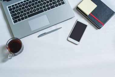 Dizüstü bilgisayar, siyah notebook, cep telefonu, kalem, bir fincan çay Üstten Görünüm
