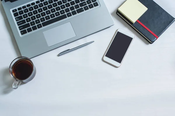 Dizüstü bilgisayar, siyah notebook, cep telefonu, kalem, bir fincan çay Üstten Görünüm
