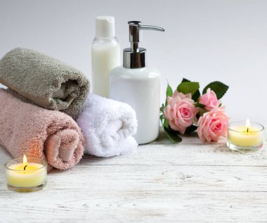 Vücut Bakımı kozmetik mumlar ve beyaz ahşap zemin üzerinde havlu ile kümesi. Güzellik spa konsept.